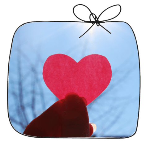 Accompagnement postpartum avec le cœur — Les Petits Pois Main tenant un cœur en papier rouge devant le ciel, symbole de l'accompagnement postpartum avec le cœur