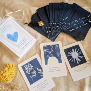 Cartes de l'Oracle des nouvelles mères étalées en éventail avec messages de soutien post-partum et illustrations au cyanotype, pochette organza blanche
